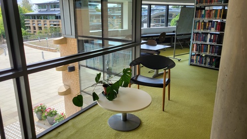 A small chair and a table with a pot plant, next to the window on the first floor, overlooking CMS