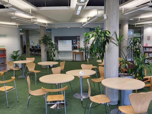 An interior photo of the ground floor of the Moore Library, detailing lots of seating, tables and green plants